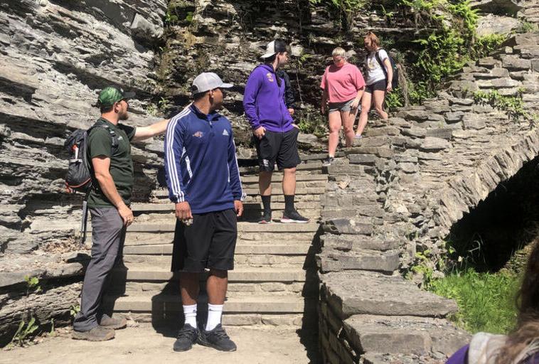 Students hike on a rocky staircase next to a waterfall